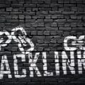 Grafite artístico em parede de tijolos escuros com a palavra BACKLINKS e correntes conectadas, ilustrando a solidez de uma estratégia de link building bem executada.