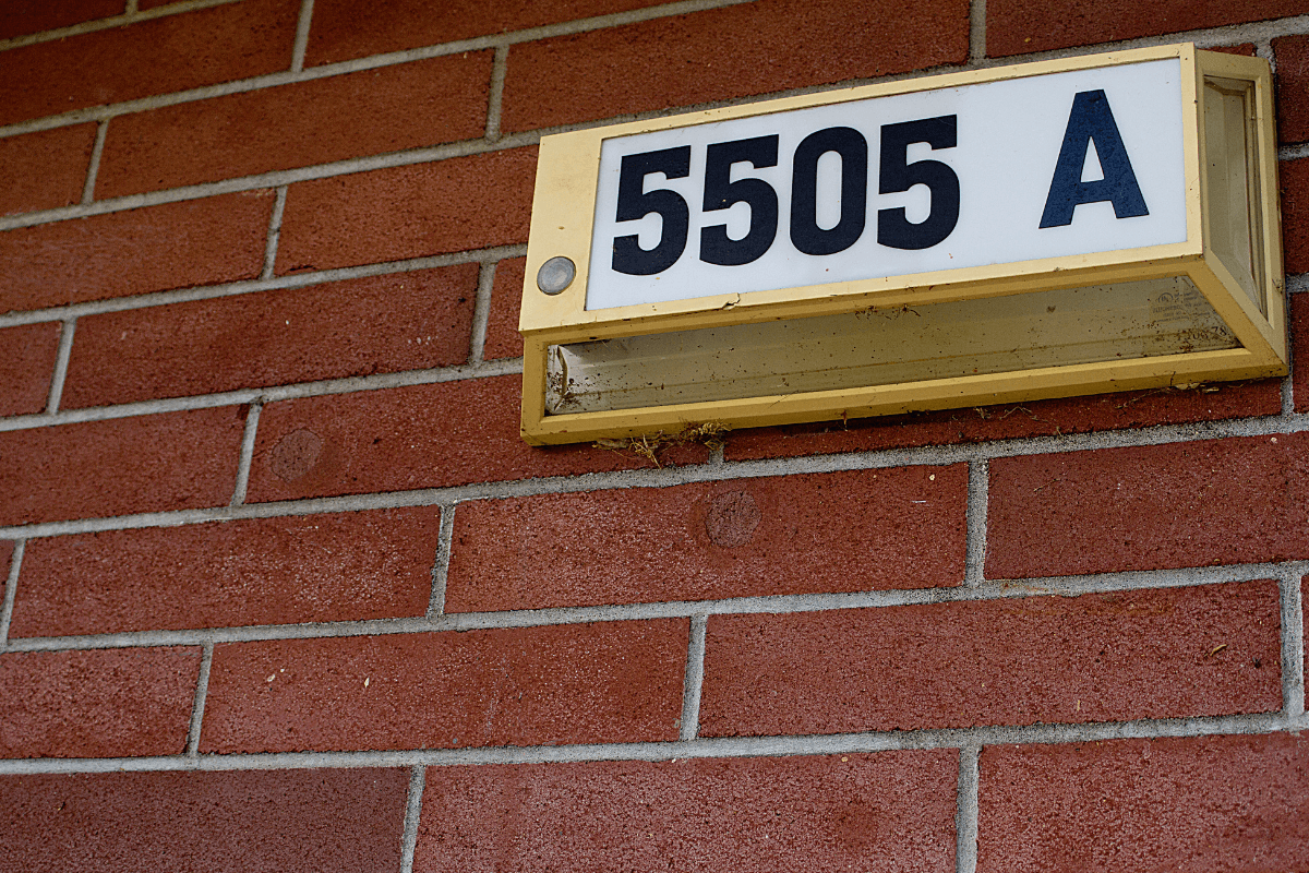 Exemplo de precisão em endereço físico para SEO Local Placa de numeração predial 5505 A em parede de tijolos ilustrando a precisão de endereço necessária para validação de dados NAP no Google.