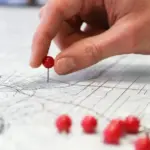 Mão fixando um alfinete vermelho no mapa para ilustrar visualmente o que é seo local e como ele destaca empresas na região.