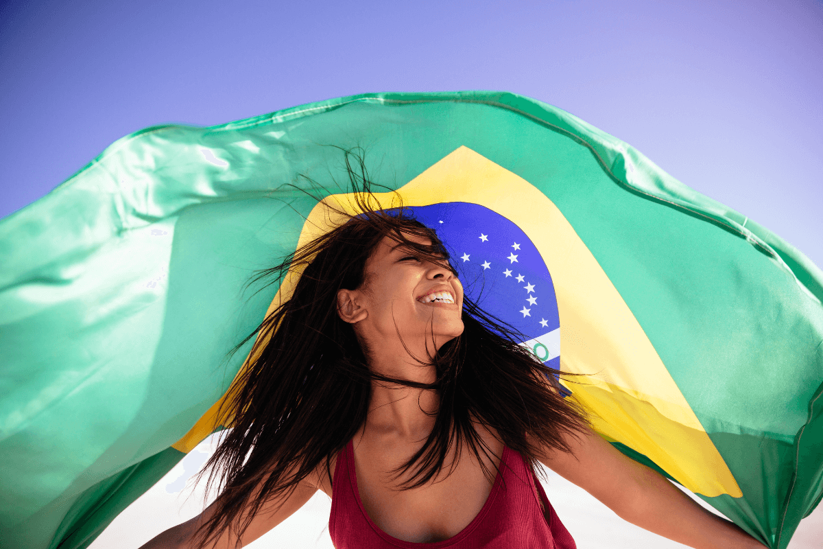 Mulher sorrindo segurando a bandeira do Brasil, ilustrando as estratégias para brasileiros ganharem em dólar no ySense.