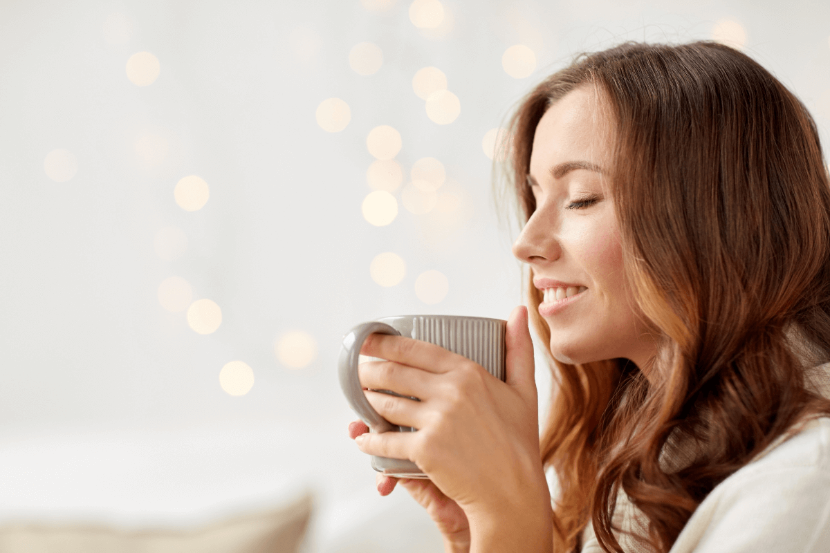 Mulher sorrindo e segurando uma xícara de café, representando a tranquilidade de quem aprendeu como conseguir backlinks de graça para seu site.