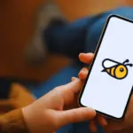 Pessoa segurando um smartphone com o logotipo do aplicativo Honeygain na tela, ilustrando o método de como ganhar dinheiro com o Honeygain através do compartilhamento de internet.