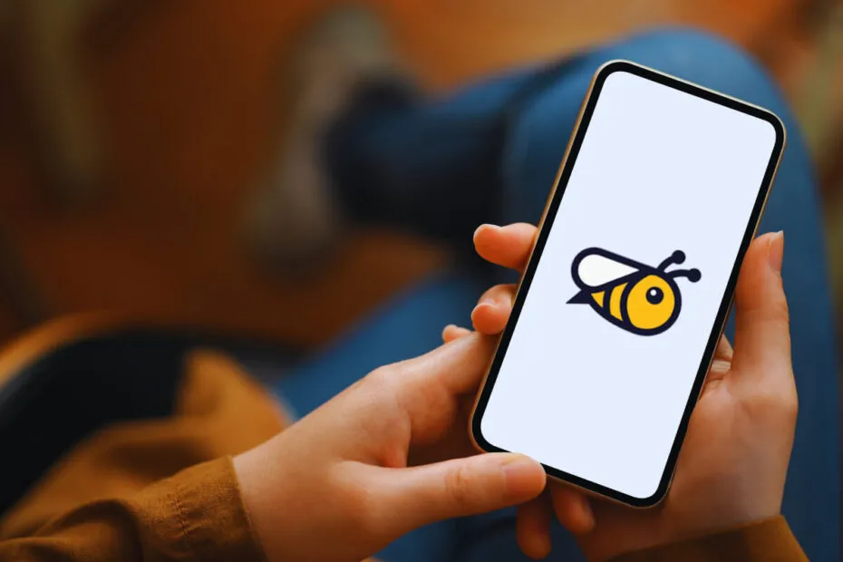 Pessoa segurando um smartphone com o logotipo do aplicativo Honeygain na tela, ilustrando o método de como ganhar dinheiro com o Honeygain através do compartilhamento de internet.