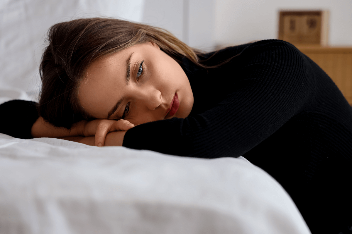 Mulher com expressão de frustração deitada na cama, representando o sentimento de ser desqualificada em pesquisas remuneradas do GrabPoints.