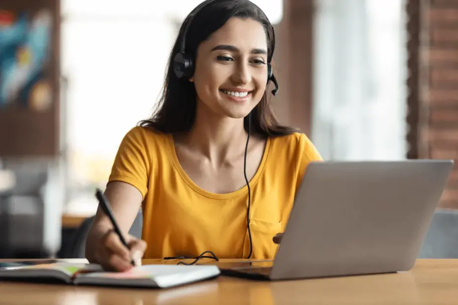 Mulher profissional sorrindo em home office com headset e notebook, ilustrando a busca por qual o primeiro passo para trabalhar na internet e iniciar uma carreira no mercado digital.
