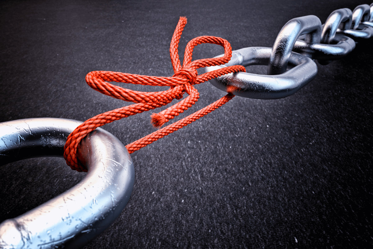 Consertando conexões com a técnica dos links quebrados Corrente de metal com um elo substituído por um nó de corda vermelha, ilustrando visualmente a técnica dos links quebrados onde você repara uma conexão perdida.